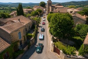 drone_voitures anciennes occitanie Prise de vue aérienne par drone d'un défilé de voitures anciennes dans un village d'Occitanie